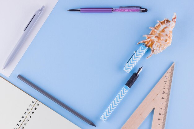 Back to school School stationery and seashell on blue background Pens pencil and gon