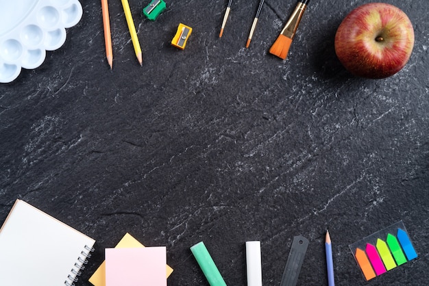 Back to school student design concept, top view of stationery over slate black table background with copy space.