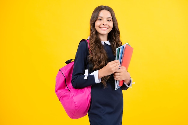 Back to school Teenager schoolgirl hold book and copybook ready to learn School children on isolated yellow studio background