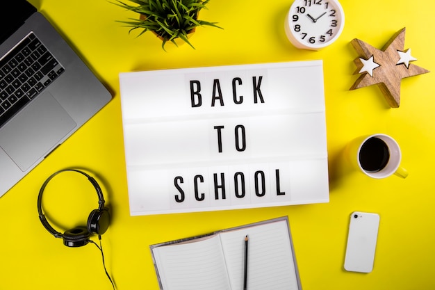 Back to school text on lightbox on modern yellow office work table