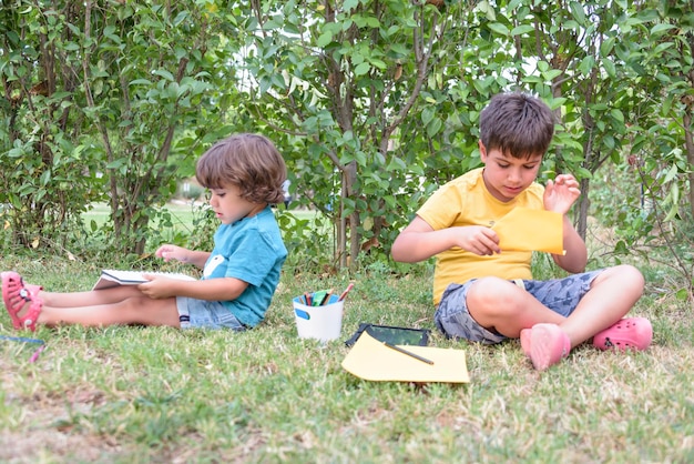 Back to school Two happy and cheerful children a schoolboy with notebooks and paints in their hands in the park