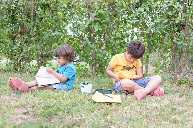 Back to school Two happy and cheerful children a schoolboy with notebooks and paints in their hands in the park