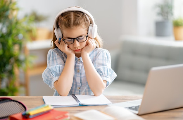 Back to school. Unhappy child is sitting at desk. Girl doing homework or online education.