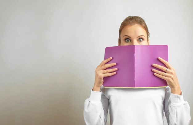 Back to school. Woman with a notebook isolated on light background.