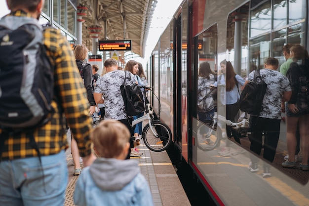 Back shot of caucasian man holding child hand walking along platform going to take train