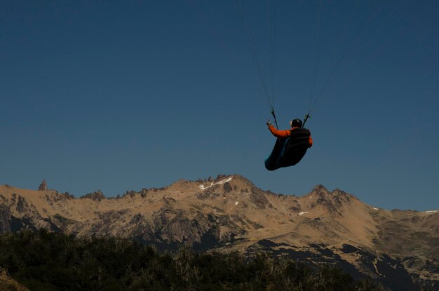 Photo back shot of paraglider flying towards the mountain with copy space