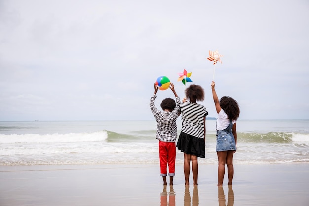 Back side of African American children standing on a tropical beach Ethnically diverse concept