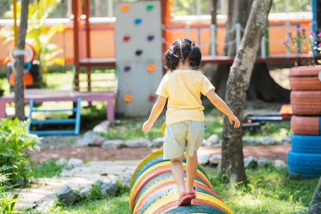 Back side Asian girl play on school or kindergarten yard or playground Healthy summer activity for children Little asian girl climbing outdoors at playground Child playing on outdoor playground