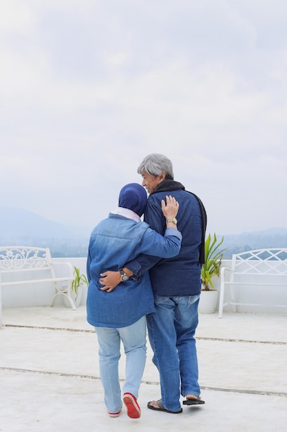 Back side of romantic mature couple hug each other and seeing landscape Happiness elderly spouse