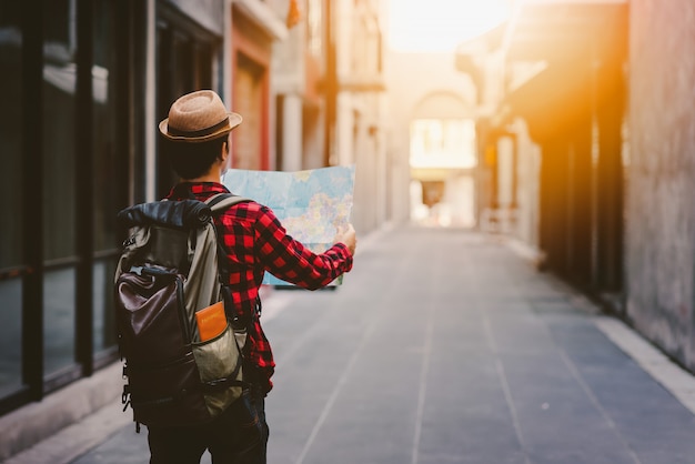 Back side of tourist man searching right direction with map on the street