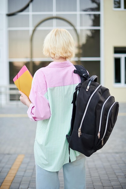 Back student girl holding books and carry school bag walking in school campus. education concept