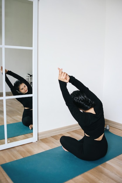 Back view of Asian woman practicing yoga and meditation in yoga studio