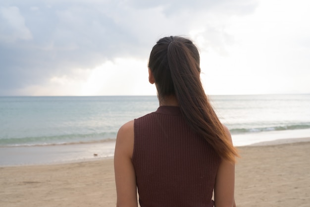 Back view of beautiful Asian tourist woman enjoying vacation