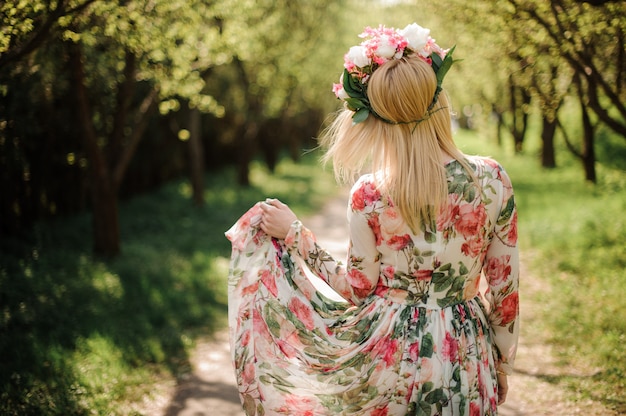 Back view of blonde woman dressed in flower dress and wreath on her head