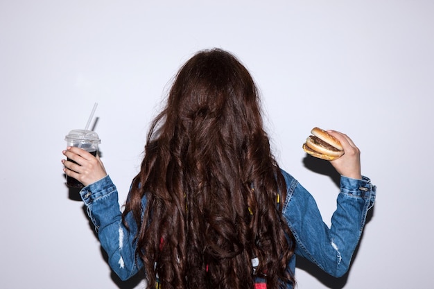 Back view of brunette woman with fast food holding in hands Unhealthy lifestyle of people and junk food concept