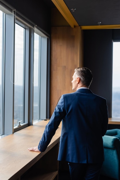 Back view of businessman in suit looking through window