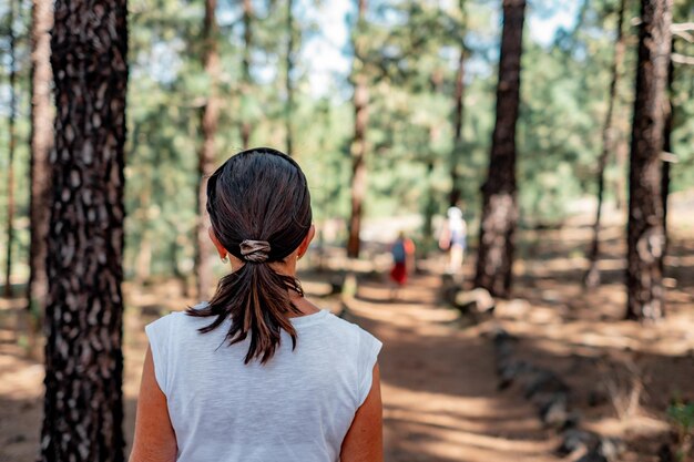 Back view of caucasian senior brunette woman walking in footpath in mountain excursion enjoying free time and freedom in nature elderly retired people and healthy lifestyle concept