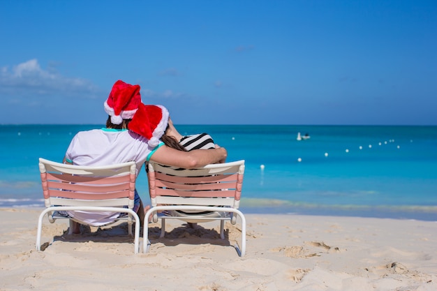 Back view of couple in Santa hats enjoy beach vacation