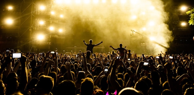 Back view of crowd of people in front of stage filming music concert with mobile phones Copy space