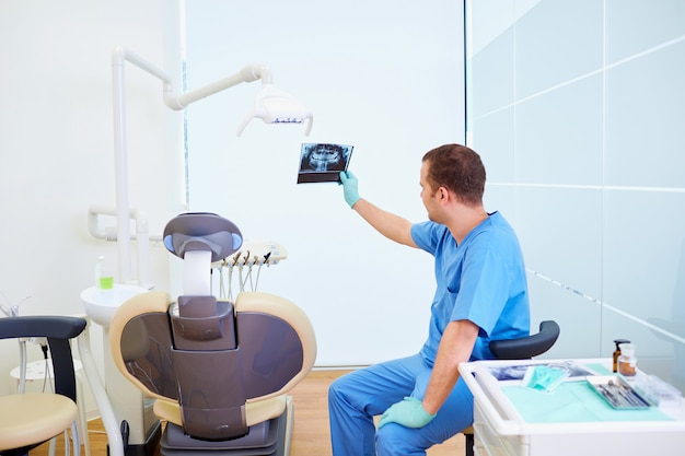 Back view a dentist man looks at an xray workplace in dental