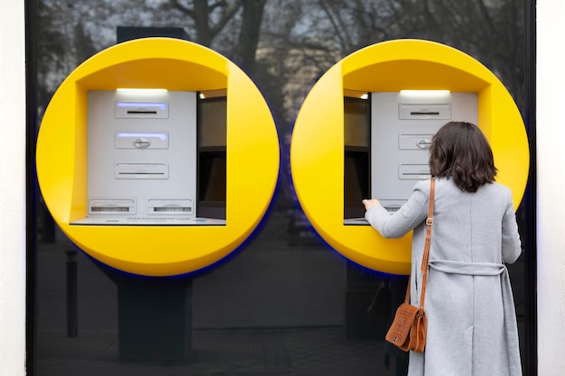 Back view of elegant woman using a modern ATM. Space for text.