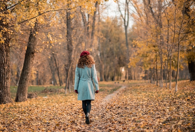 Back view of elegant young woman in gray casual coat in autumn.