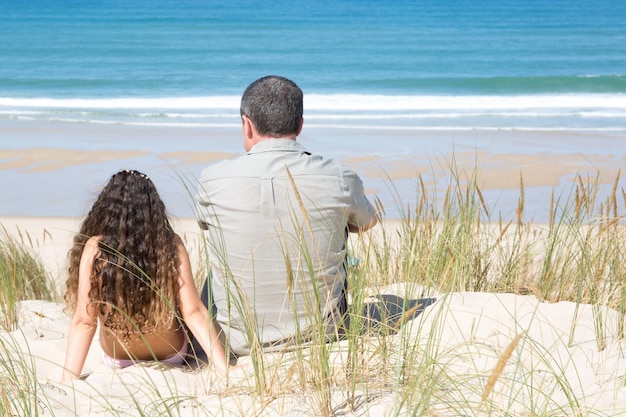 Back view of a father and his sweet daughter at beach