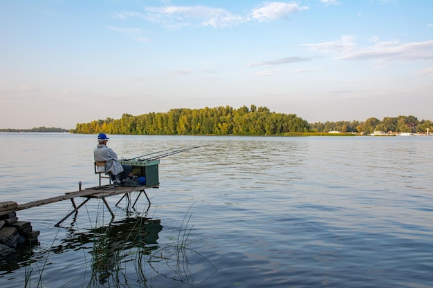 Back view of fisherman with a lot of fishing rods and a net for fish Fishing on the river