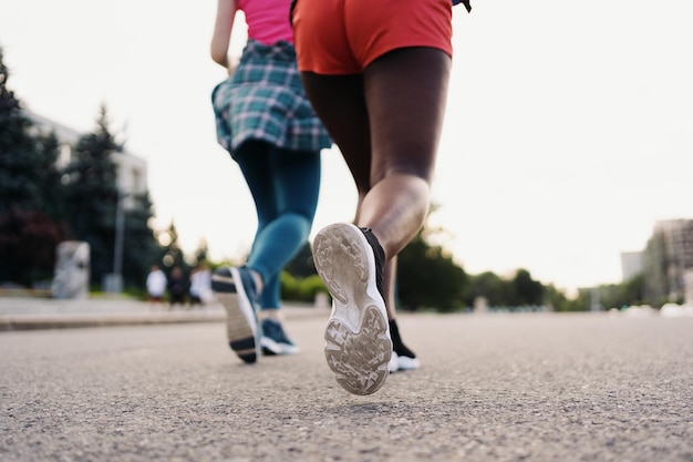 Back view of friends legs in sportswear running in the city Multiethnic women having a fitness workout