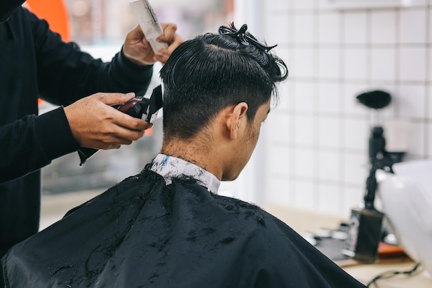 Photo back view of hairdresser shaving consumers hair with clipper