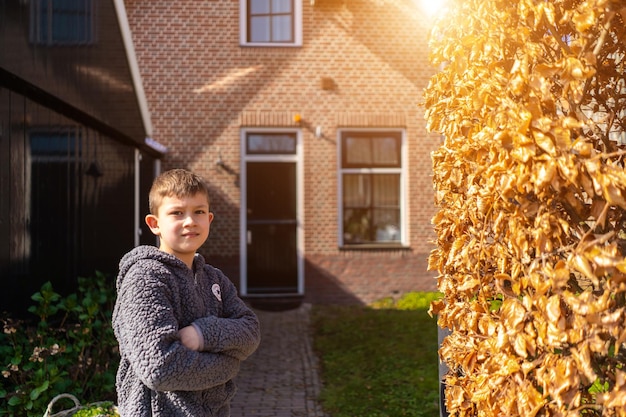 Back view of happy boy is standing near their modern house Little boy stands near the home