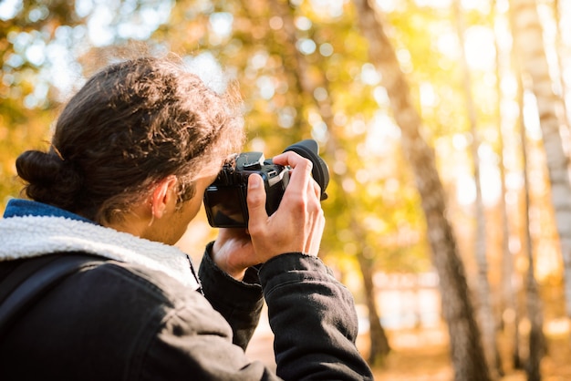 Back view of a landscape photographer shooting beautiful sunset in the park