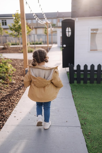 Back view of little girl walking in little kids city toy city for children outdoors road for walking