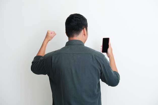 Back view of a man clenched fist showing winning gesture while looking to handphone