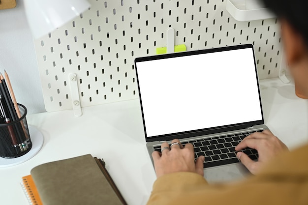 Back view of man freelancer working online with laptop computer at home office desk.