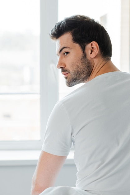 Back view of man looking away near window at home