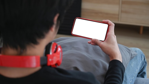 Back view of man siting on sofa and using mobile phone