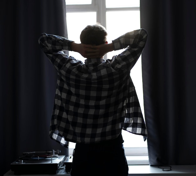 A back view of man standing in front of the window in the morning at home silhouette