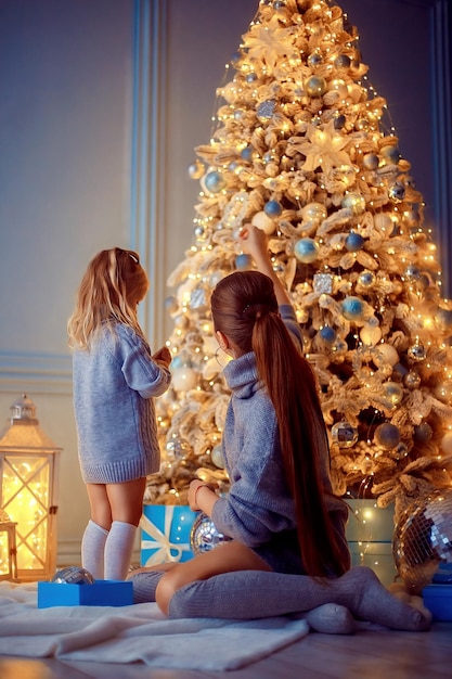 Back view of mother and daughter decorate the christmas tree together at home merry christmas