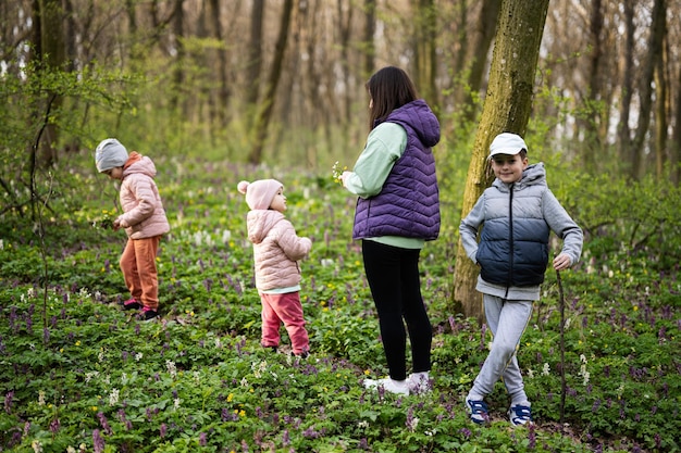 Back view of mother with three kids walking on forest trail Outdoor spring leisure concept