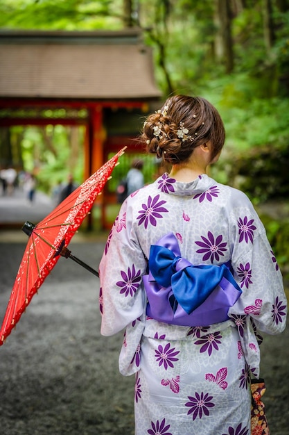 Photo back view of one woman wearing japanese yukata summer kimono and holding japanese oilpaper umbrella