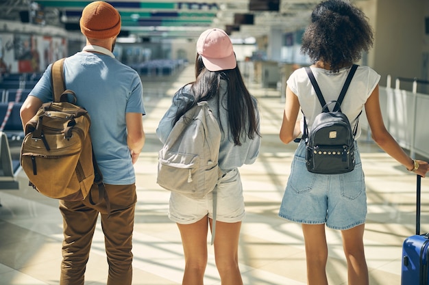 Back view portrait of happy tourist in casual clothes with backpack on shoulder thinking about something