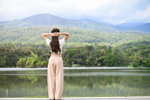 Back view Relaxed Asian female looking at amazing beautiful mountain and lake view