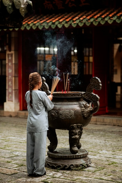 Back view of religious woman with burning incense at the temple