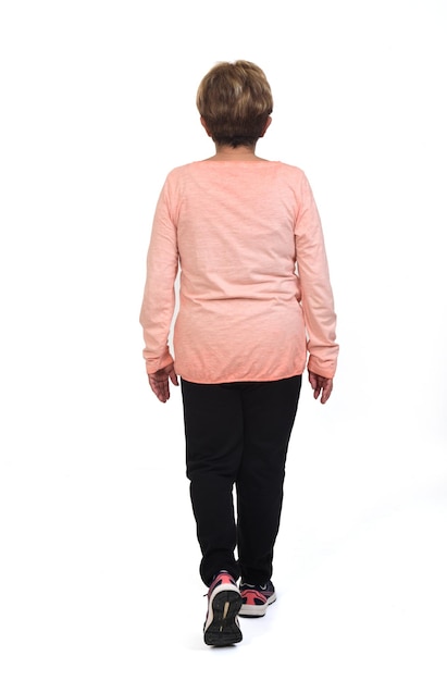 Back view of senior woman walking on white background