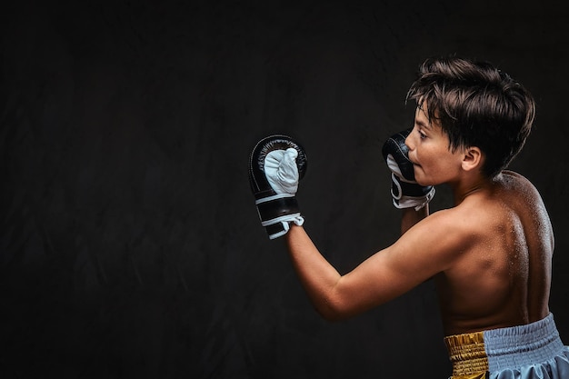 Back view of a shirtless young boxer during boxing exercises, focused on process with serious concentrated facial.