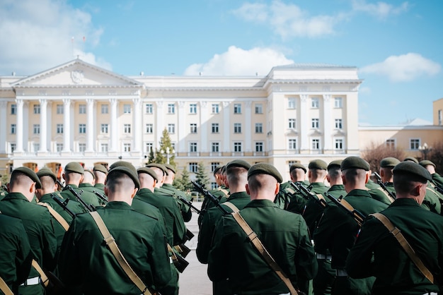 Back view of soldiers in uniform and in berets standing with weapons on city square in front of administration building, special forces. Military victory parade on May 9th. Smolensk, Russia 9.05.2021