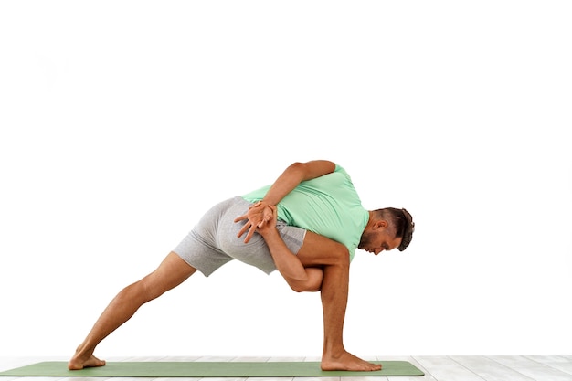 Back view of sporty man practicing yoga in yoga class making stretching back