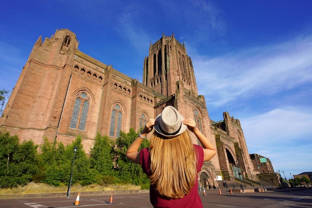 Back view of tourist girl looking the Cathedral Church of Christ against blue sky in Liverpool on sunset United Kingdom