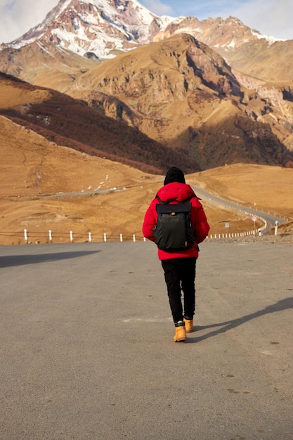 Back view of traveler with backpack hiking alone in mountainous region high quality photo